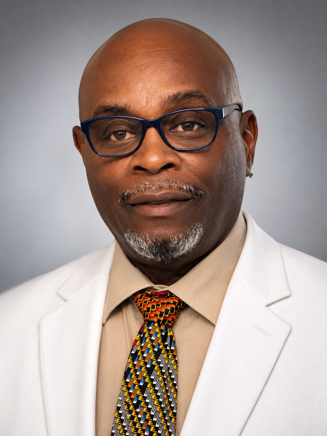 Dr. Ronald J. Stephens wearing blue glasses, a white jacket, and a patterned tie
